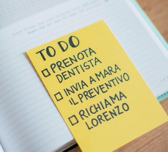 Una lista to do su cartoncino giallo con tre voci: prenota il dentista, invia a Mara il preventivo, richiama Lorenzo